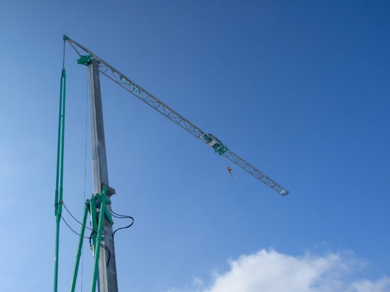 small tower crane used on a construction site to lift material for building, blue sky in background